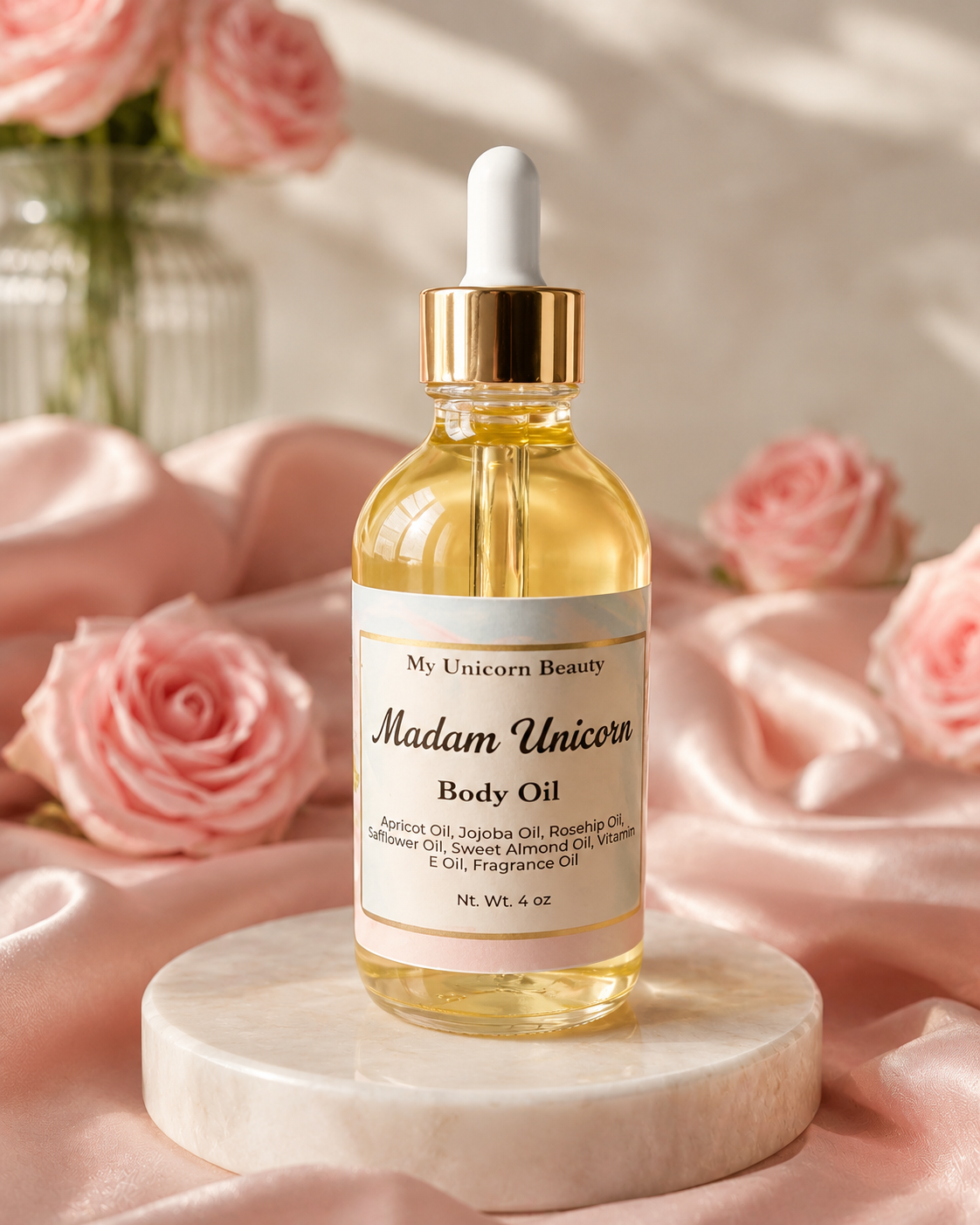 A bottle of My Unicorn Beauty 'Madam Unicorn' body oil, filled with golden-yellow oil, sits on a white marble pedestal. The bottle has a white dropper cap with a gold collar.