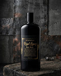 Black body wash bottle labeled 'Royal Legacy' on a rustic wooden surface with a metallic background.