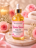A bottle of My Unicorn Beauty Madam Unicorn Body Oil stands on a round marble tray, surrounded by pink roses, white pearls, baby's breath, a lit candle, and folded white towels in a soft, spa-like setting.