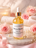 A bottle of My Unicorn Beauty Unicorn Rainbow Body Oil with a gold dropper cap, displayed on a marble slab with pink roses, white towels, and a lit candle in the background.
