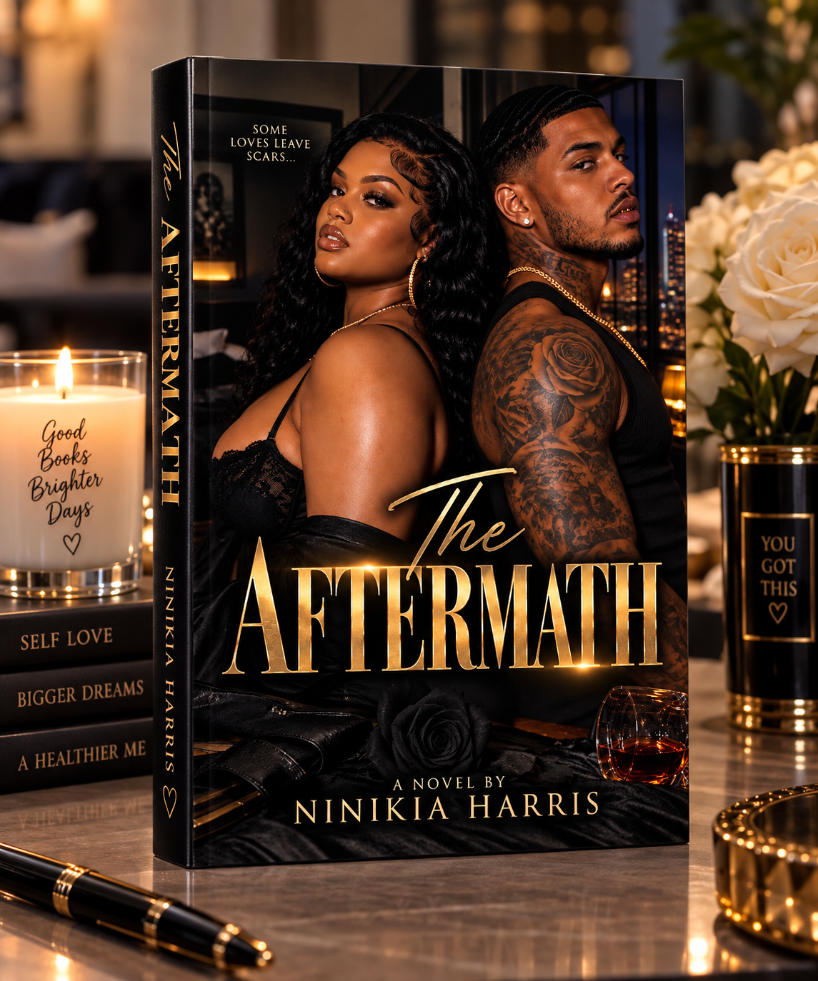 A hardcover novel titled "The Aftermath" by Ninikia Harris, standing upright on a tabletop. The cover shows a dark romantic scene with two people seated back-to-back, and the title is printed in large gold lettering.