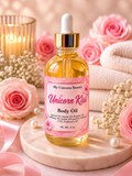 A bottle of My Unicorn Beauty Unicorn Kiss Body Oil with a pink label and gold dropper cap, styled on a marble tray with pink roses, pearls, and a candle in the background.