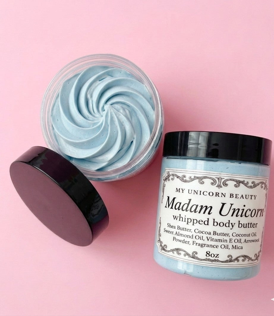 Blue whipped body butter in a jar with a black lid on a pink background
